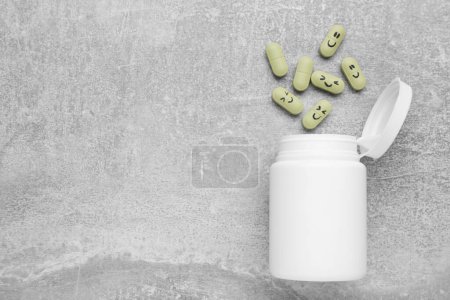Foto de Antidepresivos con emoticonos felices y frasco médico sobre fondo texturizado gris claro, tendido plano. Espacio para texto - Imagen libre de derechos