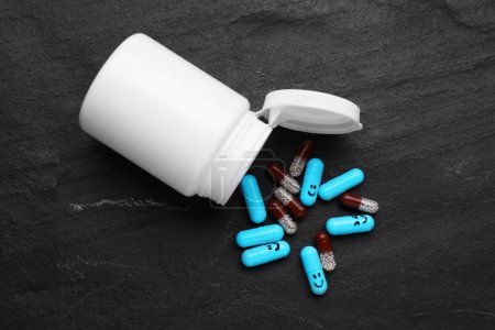 Foto de Antidepresivos con emoticonos felices y frasco médico sobre fondo negro, acostado plano - Imagen libre de derechos