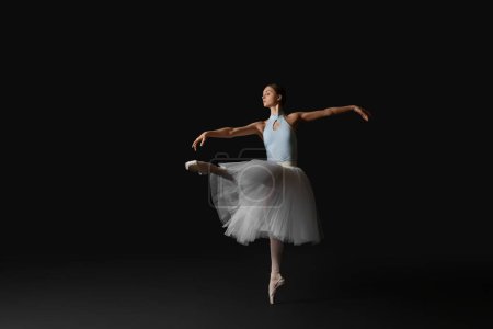 Photo for Young ballerina practicing dance moves on black background. Space for text - Royalty Free Image