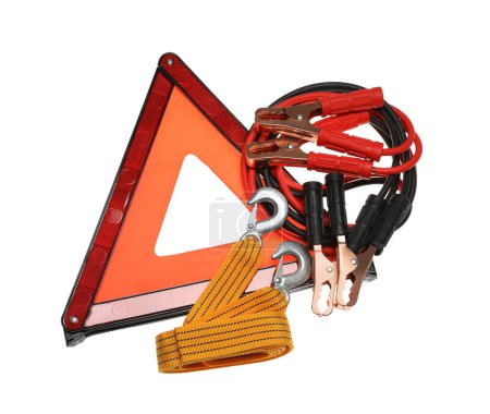 Emergency warning triangle, towing strap and battery jumper cables on white background, top view. Car safety