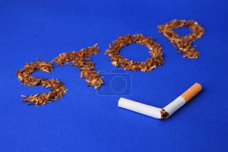 Photo for Word Stop made of dry tobacco and broken cigarette on blue background, closeup. Quitting smoking concept - Royalty Free Image