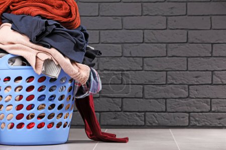 Photo for Laundry basket with clothes near black brick wall. Space for text - Royalty Free Image