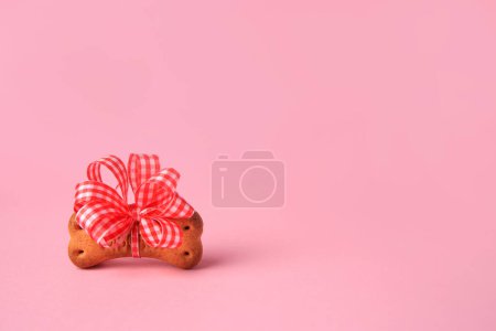 Téléchargez les photos : Bone shaped dog cookie with bright bow on pink background. Space for text - en image libre de droit