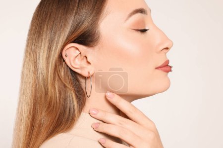 Foto de Mujer joven con piercings en los labios y las orejas sobre fondo blanco, primer plano - Imagen libre de derechos