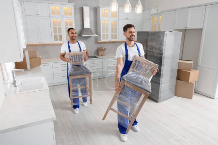 Photo for Male movers carrying chairs in new house - Royalty Free Image