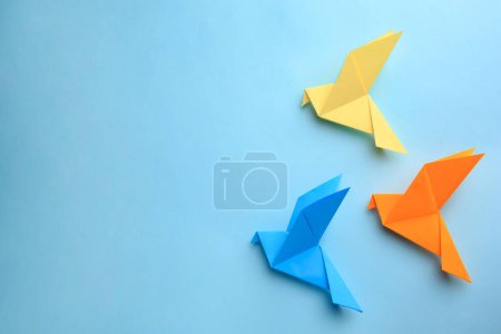 Foto de Origami art. Colorful handmade paper birds on light blue background, flat lay. Space for text - Imagen libre de derechos