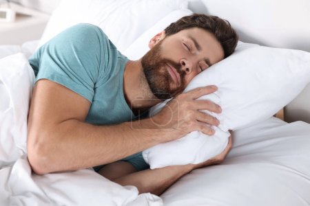 Téléchargez les photos : Homme dormant sur des oreillers confortables dans le lit à la maison - en image libre de droit
