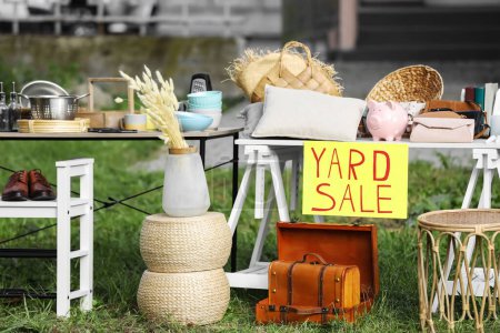 Table with different stuff and sign Yard sale outdoors