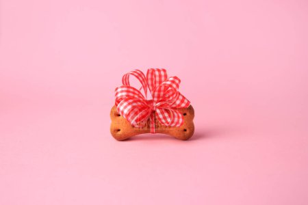 Téléchargez les photos : Bone shaped dog cookie with bright bow on pink background - en image libre de droit