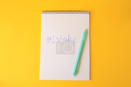 Photo for Word Mistake written with erasable pen in notepad on yellow background, top view - Royalty Free Image