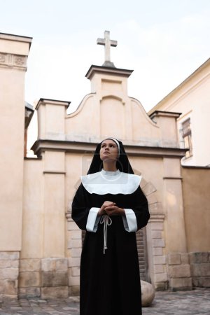 Téléchargez les photos : Beautiful young nun in cassock near cathedral outdoors - en image libre de droit