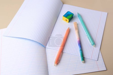 Photo for Copybooks with erasable pens and pencil sharpener on beige background - Royalty Free Image