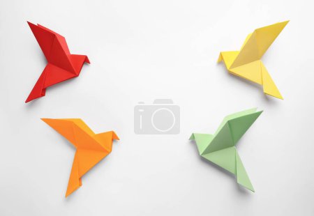 Foto de Origami art. Colorful handmade paper birds on white background, flat lay. Space for text - Imagen libre de derechos