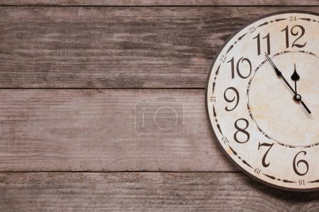 Photo for Clock showing five minutes until midnight on wooden table, top view with space for text. New Year countdown - Royalty Free Image