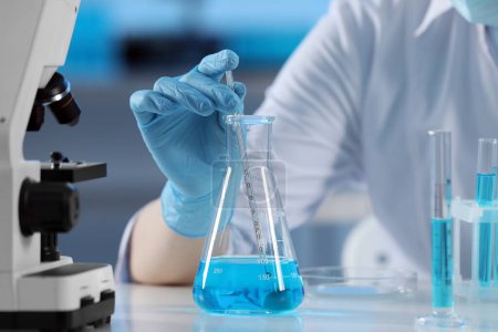 Téléchargez les photos : Scientifique prélevant un échantillon de liquide bleu clair, gros plan - en image libre de droit