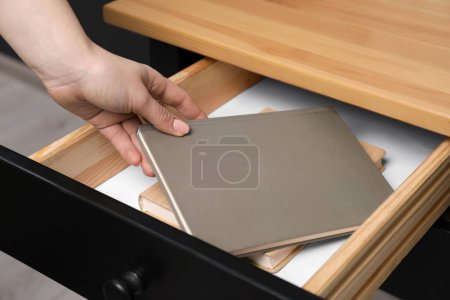 Téléchargez les photos : Woman putting notebook into desk drawer, closeup - en image libre de droit