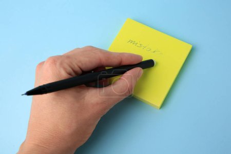Photo for Woman erasing word Mistake written with erasable pen on paper notes against light blue background, closeup - Royalty Free Image