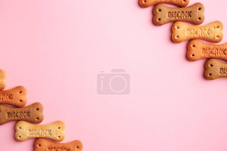 Téléchargez les photos : Bone shaped dog cookies on pink background, flat lay. Space for text - en image libre de droit