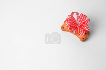 Téléchargez les photos : Bone shaped dog cookie with bow on white background, above view. Space for text - en image libre de droit