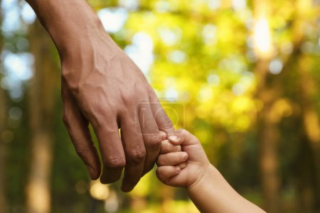 Photo for Daughter holding father's hand outdoors, closeup. Happy family - Royalty Free Image