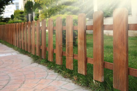 Photo for Closeup view of small wooden fence near green bushes in garden - Royalty Free Image