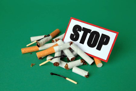 Photo for Card with word Stop, cigarette stubs and burnt matches on green background. Stop smoking concept - Royalty Free Image