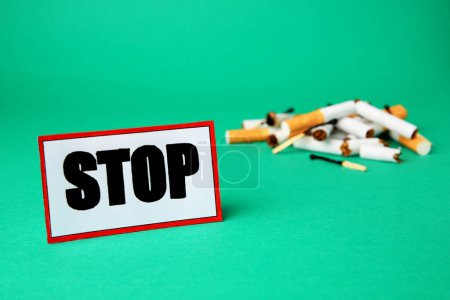 Photo for Card with word Stop near pile of cigarette stubs and burnt matches on green background. Stop smoking concept - Royalty Free Image