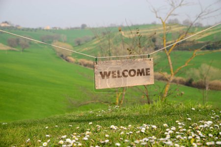 Téléchargez les photos : Welcome card. Wooden board with word hanging on rope in countryside - en image libre de droit