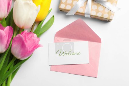 Téléchargez les photos : Welcome card, envelope, gift box and beautiful tulips on white background, flat lay - en image libre de droit