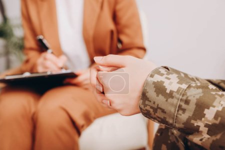 Photo for Female military officer sitting with psychologist in office, focus on hands - Royalty Free Image