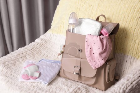 Mother's bag with baby's stuff on armchair indoors