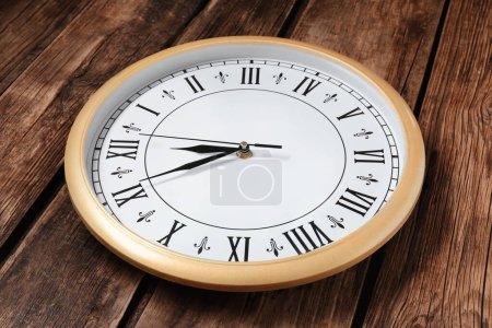 Photo for Clock showing five minutes until midnight on wooden table, closeup. New Year countdown - Royalty Free Image