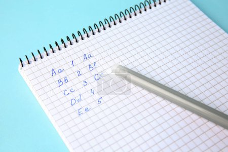Photo for Letters and numbers written in notepad with erasable pen on light blue background, closeup - Royalty Free Image
