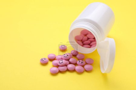 Photo for Pink antidepressants with different emoticons on yellow background - Royalty Free Image