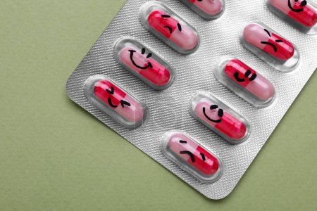 Foto de Antidepresivos con diferentes emoticonos sobre fondo verde claro, vista superior - Imagen libre de derechos