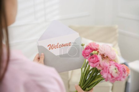 Téléchargez les photos : Welcome card. Woman holding envelope and ranunculus flowers on indoors, closeup - en image libre de droit