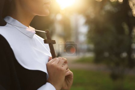 Téléchargez les photos : Young nun with Christian cross outdoors on sunny day, closeup. Space for text - en image libre de droit