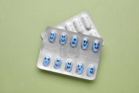 Foto de Diferentes antidepresivos con emoticonos felices sobre fondo verde claro, posición plana - Imagen libre de derechos