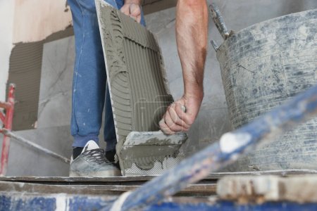 Foto de Trabajador aplicando cemento en azulejos de la pared para la instalación en interiores, primer plano - Imagen libre de derechos