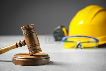 Construction and land law concepts. Judge gavel, tape measure with hardhat on light grey table, space for text