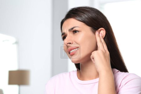 Photo for Young woman suffering from ear pain indoors, space for text - Royalty Free Image