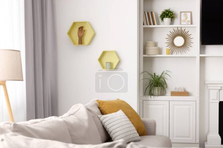 Ambiente primaveral. Sofá suave, lámpara y estantes con accesorios elegantes en la habitación