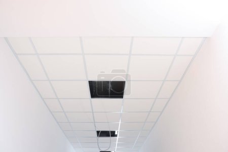 Téléchargez les photos : Low angle view on PVC tiles. Installing ceiling lighting - en image libre de droit