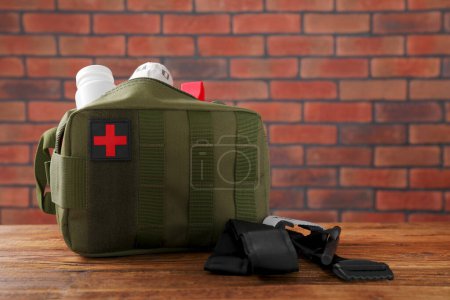 Photo for Military first aid kit and tourniquet on wooden table - Royalty Free Image