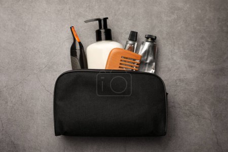 Photo for Preparation for spa. Compact toiletry bag with different cosmetic products on grey textured background, top view - Royalty Free Image