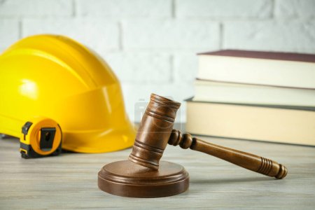 Foto de Construction and land law concepts. Judge gavel, protective helmet, tape measure with books on wooden table - Imagen libre de derechos