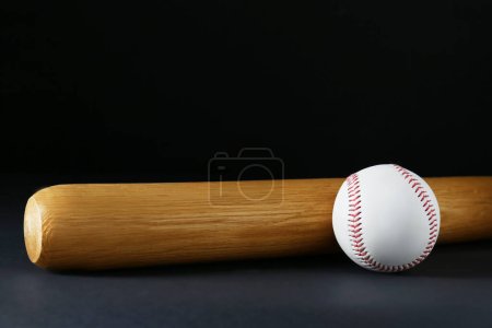 Wooden baseball bat and ball on black background, space for text. Sports equipment