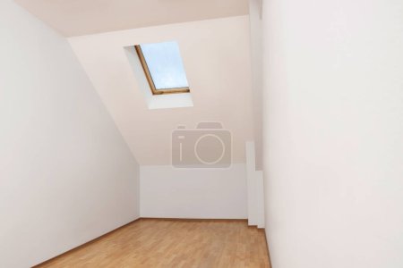 Foto de Light spacious attic room with window on slanted ceiling - Imagen libre de derechos