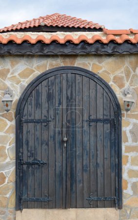 Foto de Entrance of building with beautiful arched wooden door in stone wall outdoors - Imagen libre de derechos