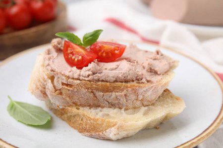 Foto de Delicious liverwurst sandwich with tomatoes and basil on table, closeup - Imagen libre de derechos